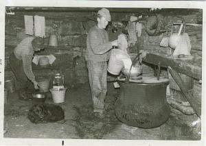 Nella casera dell'alpe Campo Pali Luciano, con il cane Rolf ai piedi, versa caldaia di rame il latte appena munto mentre D'Andrea Aldo si appresta a preparare la polenta (1969)